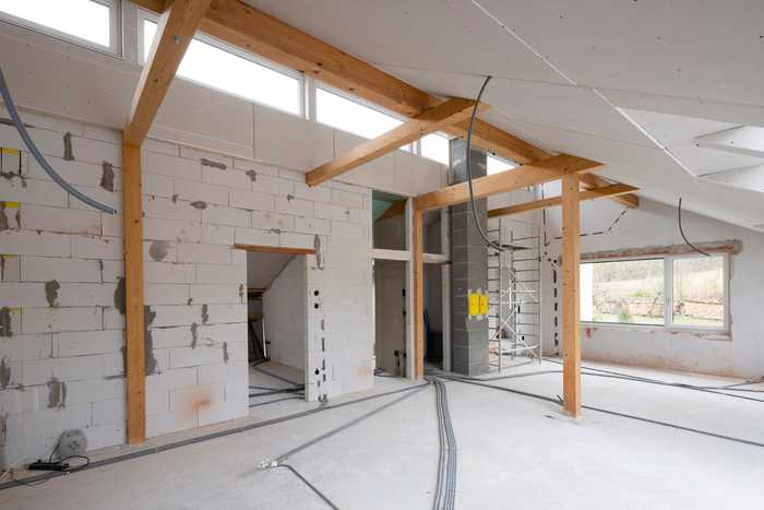 A picture of an unfinished extension with exposed block work, unfinished walls, and a new wooden supporting structure for a wall